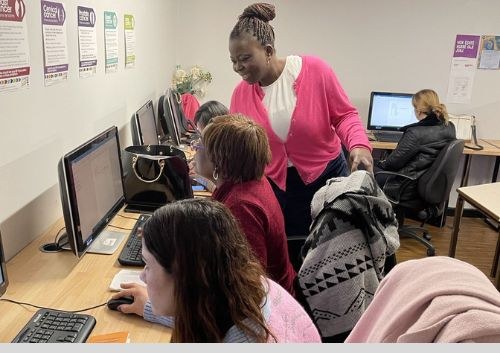 A tutor helping a learner at a laptop