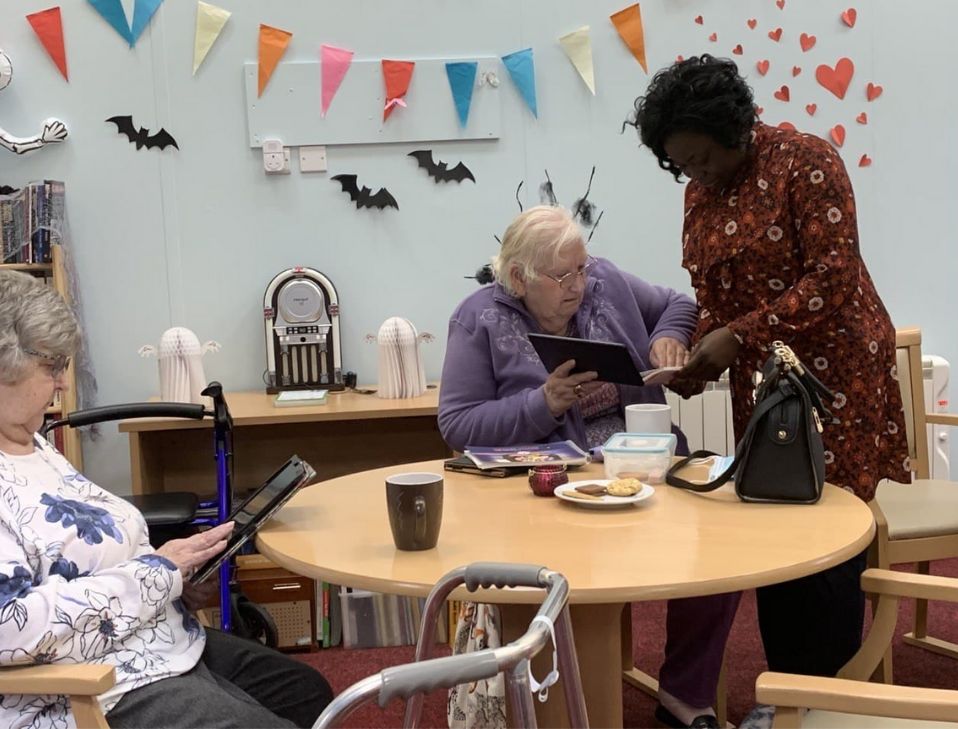 An older learner using a tablet with Yetunde beside her
